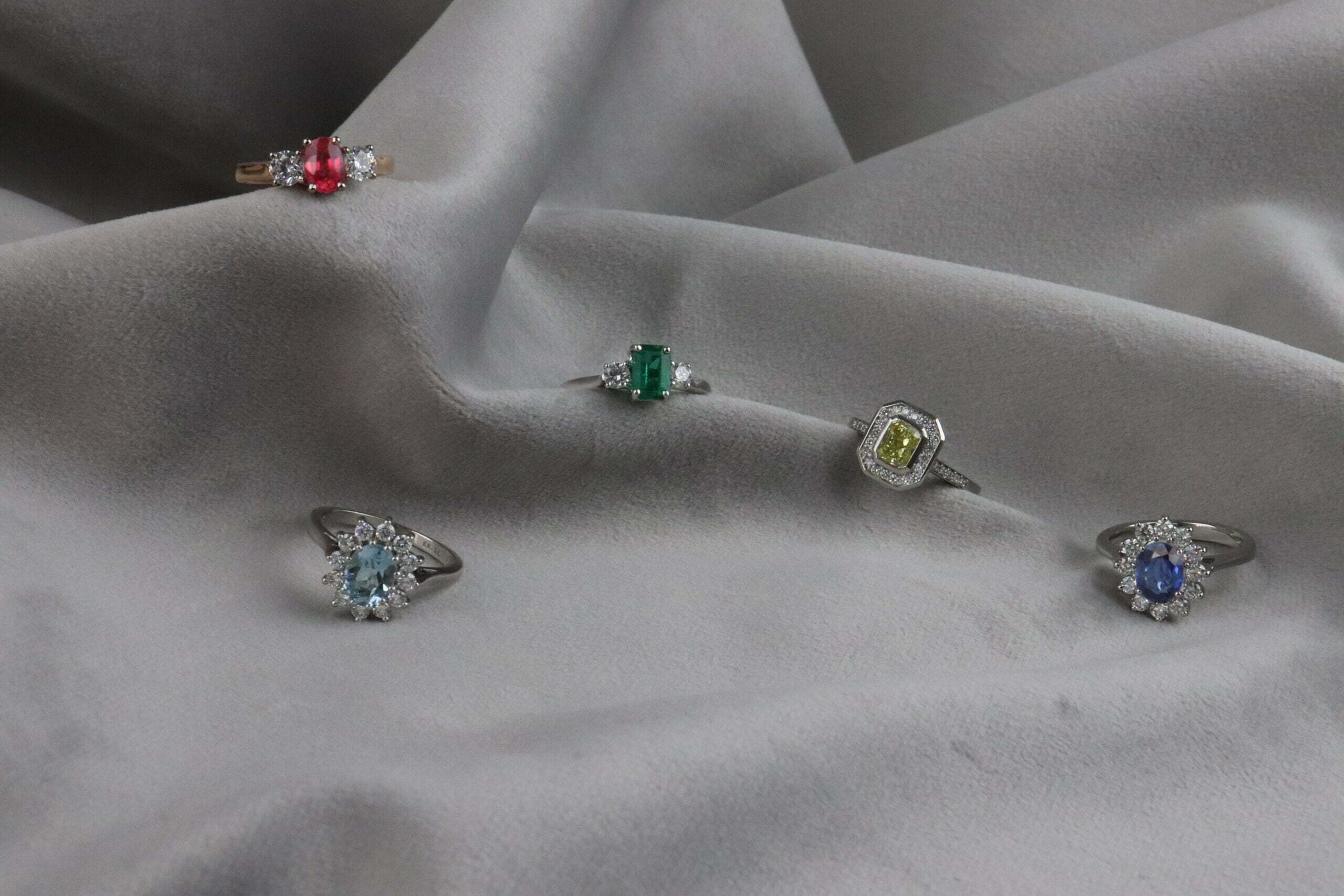 Sapphire halo, emerald solitaire, ruby cluster. Three rings, one tray.